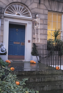 Blue door with pumpkins , webs and a skeleton.
