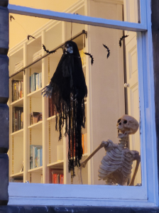 Window with a black ghoul and a white skeleton waving.