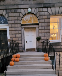 White front door with pumpkins at either side.