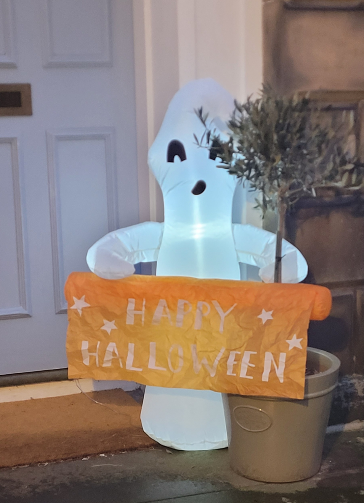 White ghost holding a orange sign saying Happy Halloween